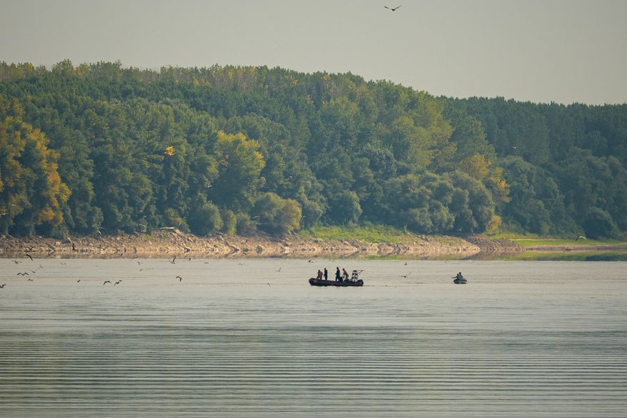 Romanian Navy EOD specialists survey the area before a controlled demolition of submerged rocks to improve water flow to the Cernavoda Nuclear Power Plant amid exceptionally low water levels on the Danube River, in Izvoarele, Romania, Monday, Aug. 3 2026. (AP Photo/ Vadim Ghirda)