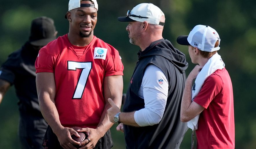 Atlanta Falcons running back Bijan Robinson (7) speak to a coach during a Atlanta Falcons training camp, Monday, Aug. 3, 2026, in Flowery Branch, Ga. (AP Photo/Mike Stewart)