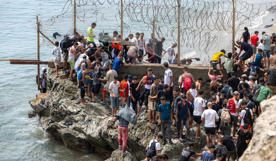 People breach barbed wires as they attempt to cross from the Moroccan northern town of Fnideq to the Spanish enclave of Ceuta, Friday, July 31, 2026. (AP Photo)
