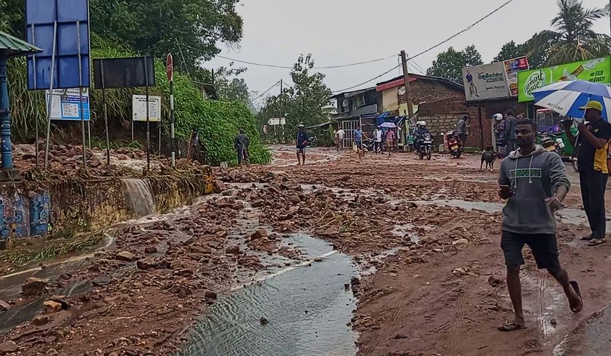 People walk across a mud covered road following heavy rain in Nawalapitiya, Sri Lanka, Tuesday, Aug. 4, 2026. (AP Photo)