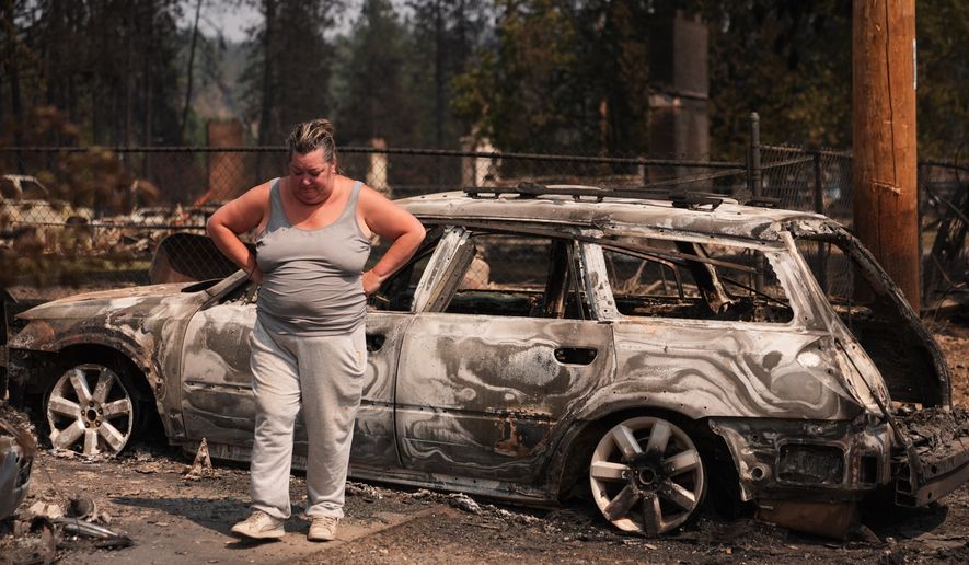 Michelle Angstrom reacts to her burned down home and property after a wildfire hit the northwest part of Spokane, Wash., Tuesday, Aug. 4, 2026. (AP Photo/Lindsey Wasson)
