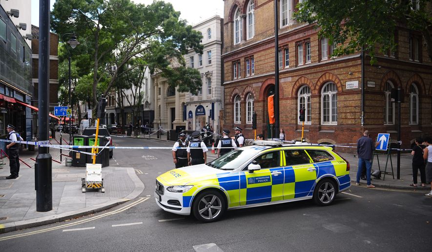 Police officers stand at the scene on Endell Street in Covent Garden, after four men were stabbed, in central London, Wednesday Aug. 5, 2026. PA Photo. (James Manning/PA via AP)