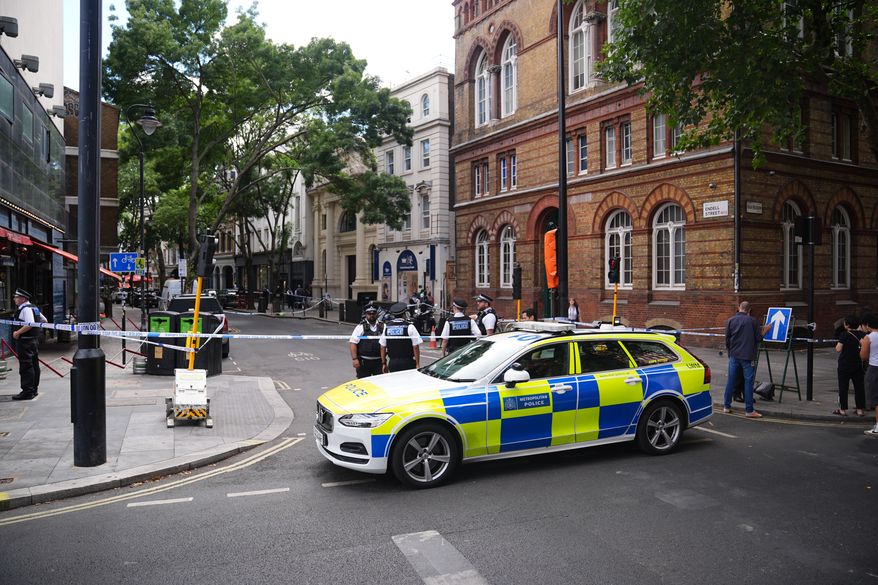 Police officers stand at the scene on Endell Street in Covent Garden, after four men were stabbed, in central London, Wednesday Aug. 5, 2026. PA Photo. (James Manning/PA via AP)