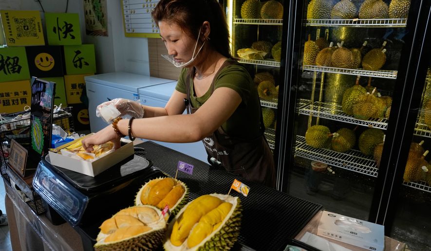 Worker Hou Yuxin packs durian fruit imported from Malaysia for delivery for a customer at a shop in Beijing, China, Monday, July 13, 2026. (AP Photo/Andy Wong)