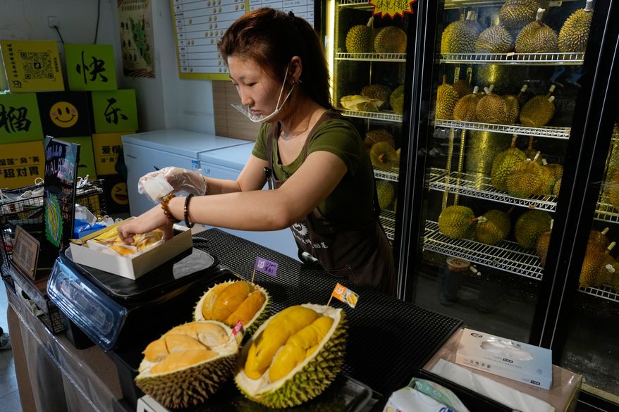 Worker Hou Yuxin packs durian fruit imported from Malaysia for delivery for a customer at a shop in Beijing, China, Monday, July 13, 2026. (AP Photo/Andy Wong)