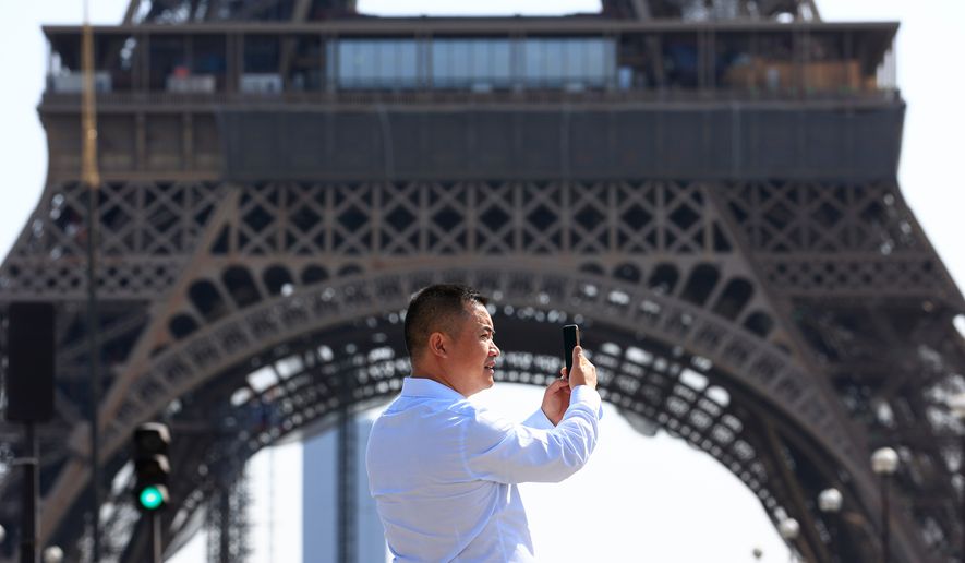 FILE - A person uses his phone near the Eiffel Tower in Paris, Wednesday, Aug. 31, 2022. (AP Photo/Aurelien Morissard, File)