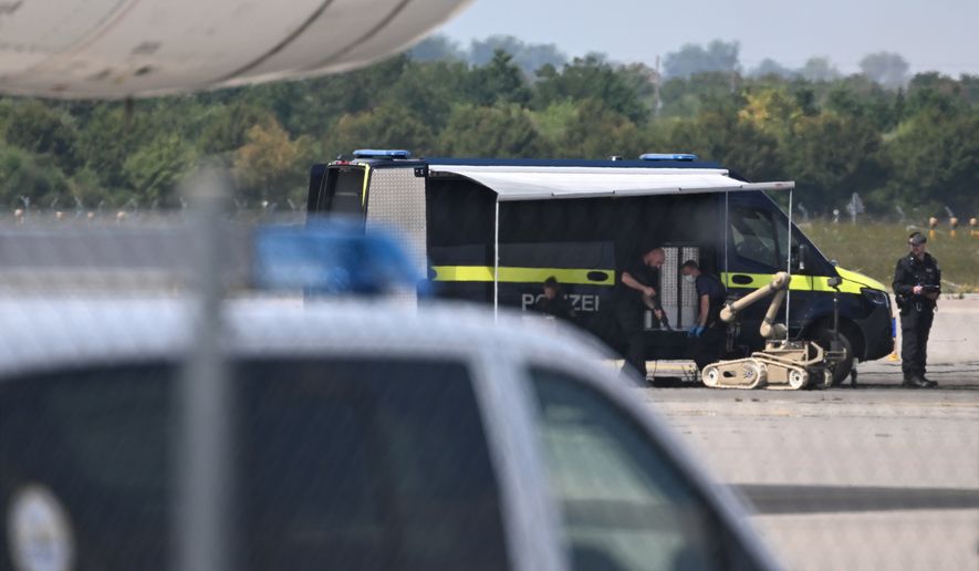 Police forensic technicians prepare to deploy an explosive-disposal robot near a Ukrainian aircraft at Leipzig/Halle Airport, in Schkeuditz, Germany, Wednesday Aug. 5, 2026, where flight operations were suspended overnight after a drone sighting was reported and another object was found near a runway. (Hendrik Schmidt/dpa via AP)