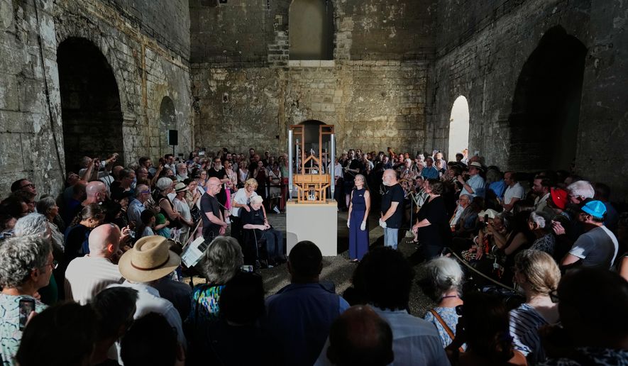 People listen to the sound of the John Cage Organ Project Halberstadt during a chord change of the organ inside the medieval Burchardi Church in Halberstadt, Germany, Wednesday, Aug. 5, 2026. (AP Photo/Markus Schreiber)