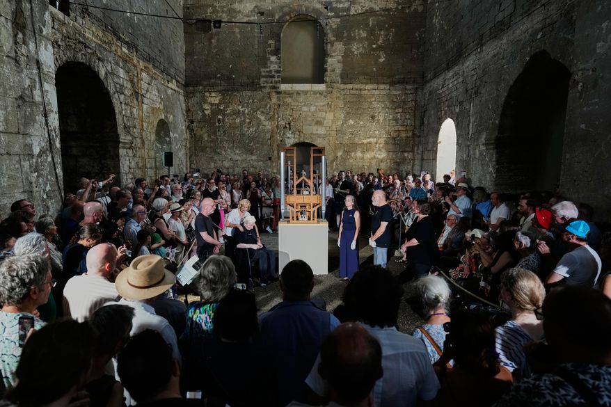 People listen to the sound of the John Cage Organ Project Halberstadt during a chord change of the organ inside the medieval Burchardi Church in Halberstadt, Germany, Wednesday, Aug. 5, 2026. (AP Photo/Markus Schreiber)