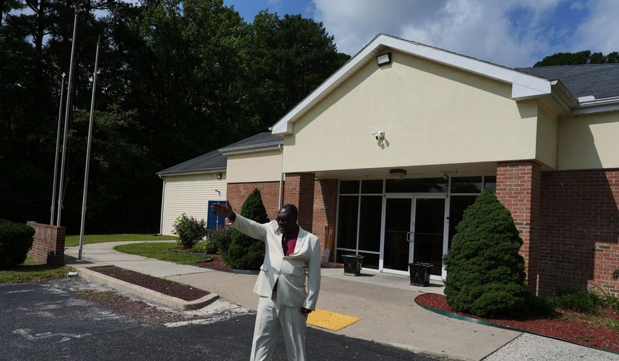 Roosevelt Toussaint, the senior pastor of the Word of Life Center church, points to empty parking spaces outside his church before a service, which he says is due to fear in the Haitian community of possible arrests and deportation in Salisbury, Md., Sunday, Aug. 2, 2026. (AP Photo/Luis Andres Henao)