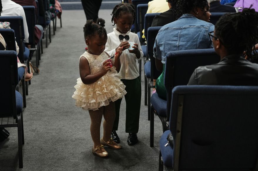 Children walk the aisles of the Word of Life Center church carrying snacks during a service in Salisbury, Md. Sunday, Aug. 2, 2026. (AP Photo/Luis Andres Henao)