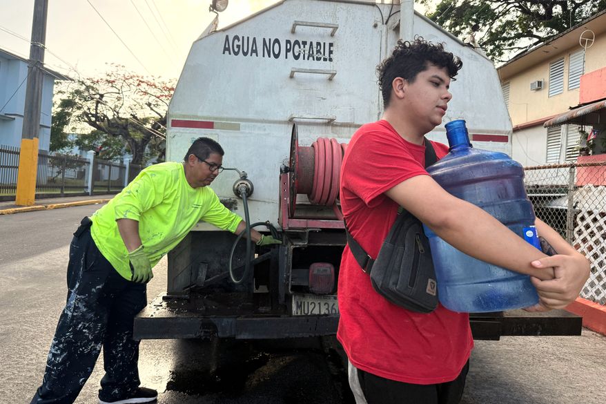 FILE - Bryan Pérez hauls a five-gallon water jug to his apartment in the Villa Kennedy public housing complex in San Juan, Puerto Rico, June 10, 2026. (AP Photo/Danica Coto, File)