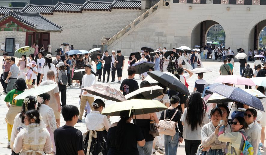 Visitors hold umbrellas to avoid sunshine at the Gyeongbok Palace in Seoul, South Korea, Wednesday, Aug. 5, 2026. (AP Photo/Ahn Young-joon)