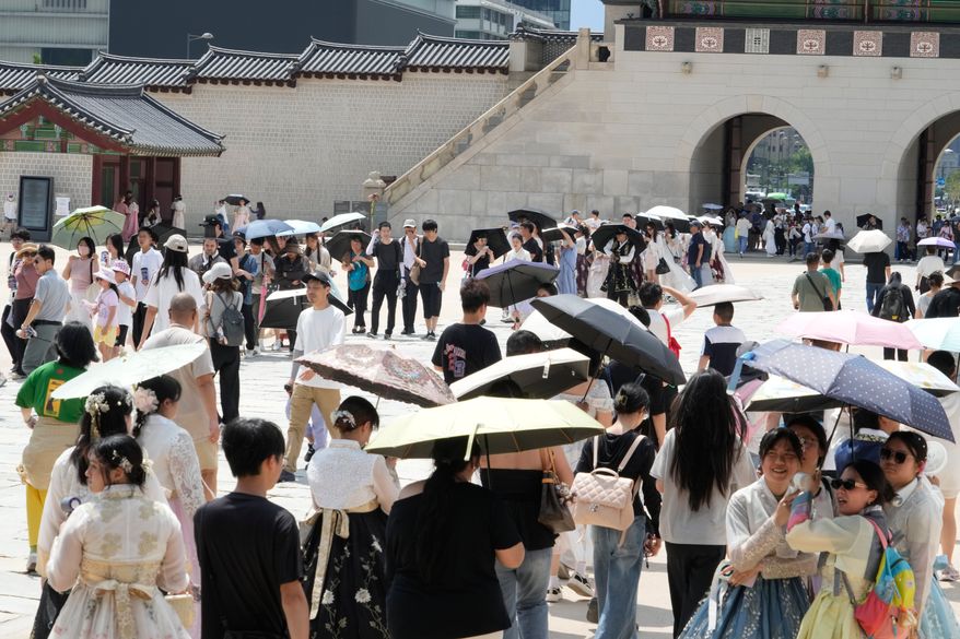 Visitors hold umbrellas to avoid sunshine at the Gyeongbok Palace in Seoul, South Korea, Wednesday, Aug. 5, 2026. (AP Photo/Ahn Young-joon)