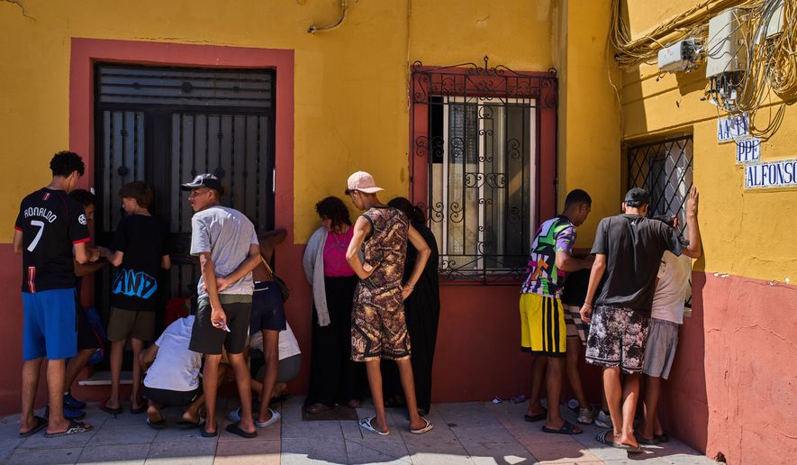 Migrants, some of them unaccompanied minors, who crossed from Morocco into Spain, write down their contact information to give to a neighborhood association in the Spanish enclave of Ceuta, Tuesday, Aug. 4, 2026. (AP Photo/Bernat Armangue)