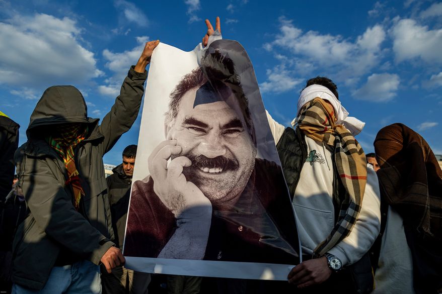 Youngsters hold a photograph of Abdullah Ocalan, the jailed leader of the militant Kurdish group, or PKK, in Diyarbakir, Turkey, Feb. 27, 2025. (AP Photo/Metin Yoksu, File)