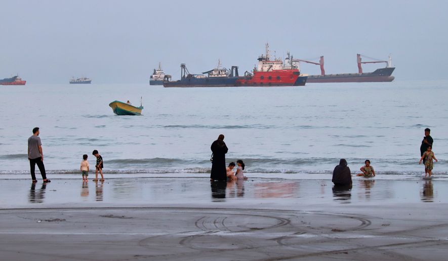 People spend time at a beach as commercial vessels are anchored in the Strait of Hormuz off Bandar Abbas, Iran, Wednesday, Aug. 5, 2026. (Amirhosein Khorgooi/ISNA via AP)