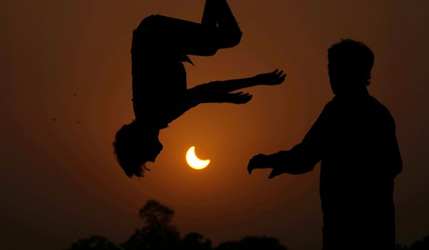 FILE - The partial solar eclipse is framed by youngsters jumping on a trampoline in the outskirts of Lahore, Pakistan, Oct. 25, 2022. (AP Photo/K.M. Chaudary, File)