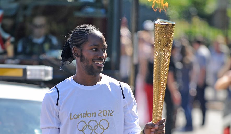Torchbearer Jason Arday carries the Olympic Flame on the Torch Relay leg between Sutton and Merton, in London, July 23, 2012. (Joe Giddens/LOCOG/PA via AP)