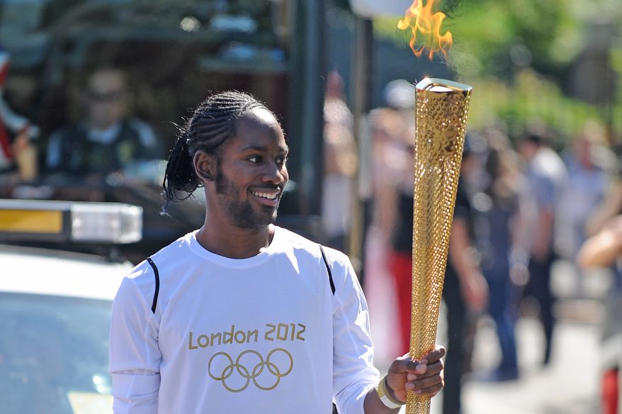 Torchbearer Jason Arday carries the Olympic Flame on the Torch Relay leg between Sutton and Merton, in London, July 23, 2012. (Joe Giddens/LOCOG/PA via AP)
