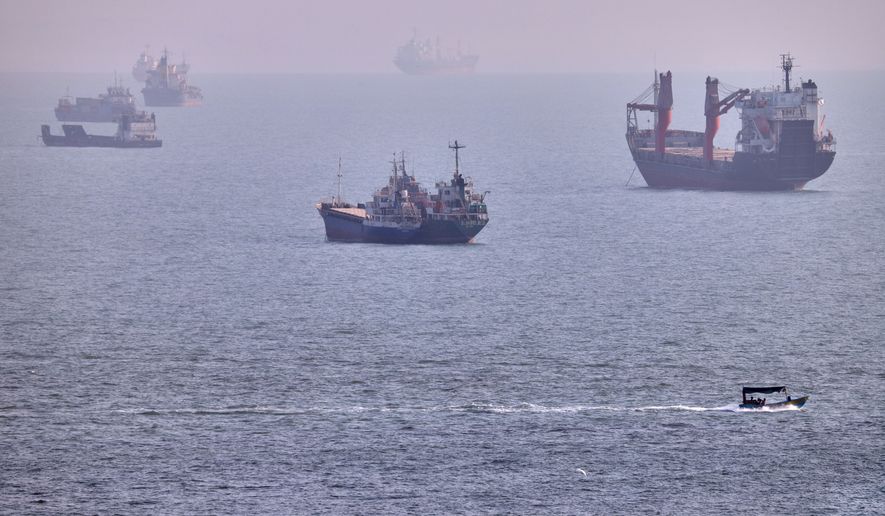A small boat sails past cargo ships and other commercial vessels anchored in the Strait of Hormuz off Bandar Abbas, Iran, Wednesday, Aug. 5, 2026. (Amirhosein Khorgooi/ISNA via AP)