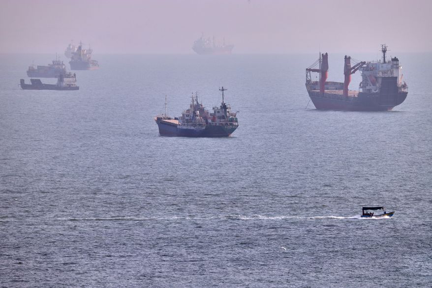 A small boat sails past cargo ships and other commercial vessels anchored in the Strait of Hormuz off Bandar Abbas, Iran, Wednesday, Aug. 5, 2026. (Amirhosein Khorgooi/ISNA via AP)