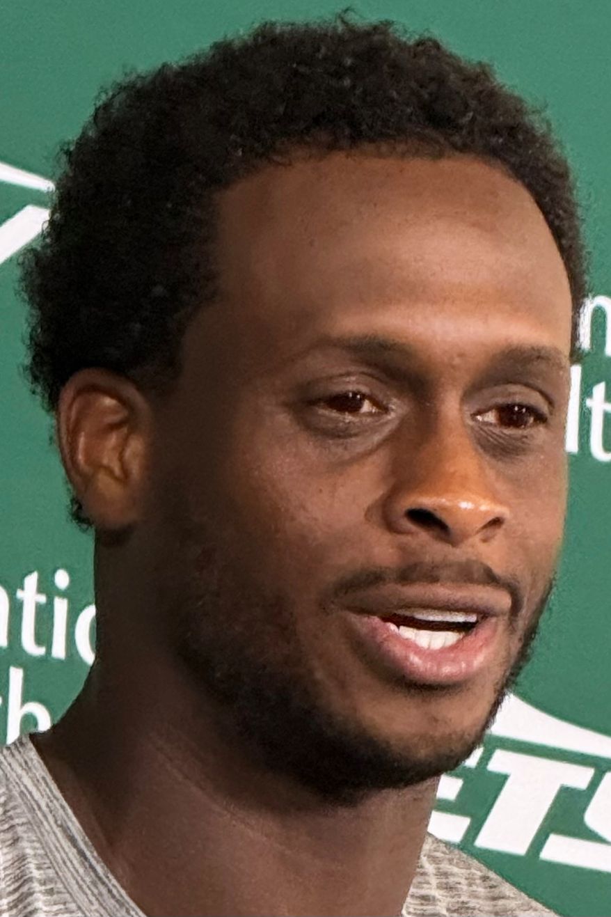 New York Jets quarterback Geno Smith, wearing red contact lenses, speaks to reporters after practice at the team’s training facility in Florham Park, N.J., on Thursday, Aug. 6, 2026. (AP Photo/Dennis Waszak Jr.)