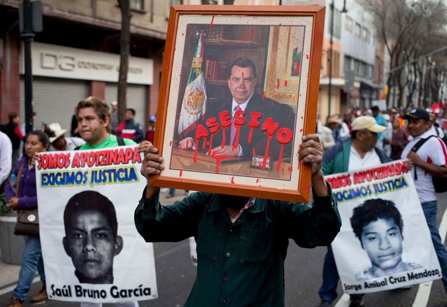 FILE - A protestor holds a portrait of Angel Aguirre, the former governor of Guerrero state, with the Spanish word for assassin written across it, during a march against the disappearance of 43 students from a rural teachers' college, Jan. 26, 2015, in Mexico City. (AP Photo/Eduardo Verdugo, File)