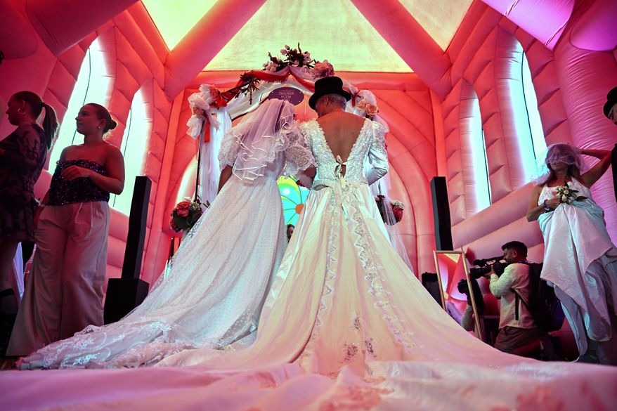 A couple prepare to exchange vows during a mass wedding ceremony in an inflatable chapel in Amsterdam, Netherlands, Thursday, Aug. 6, 2026, as part of Pride events celebrating 25 years since the Netherlands became the first country in the world to legalize same-sex marriage. (AP Photo/Mouneb Taim)