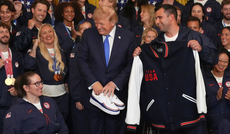 President Donald Trump poses with alpine monoskier Laurie Stephens, left, and bobsledder Frank Del Duca, right, who presented him with gifts, during an event for Olympic winter athletes, coaches, staff, and representatives from Team USA in the East Room of the White House, Thursday, Aug. 6, 2026, in Washington. (AP Photo/Alex Brandon)