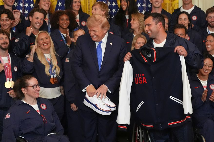 President Donald Trump poses with alpine monoskier Laurie Stephens, left, and bobsledder Frank Del Duca, right, who presented him with gifts, during an event for Olympic winter athletes, coaches, staff, and representatives from Team USA in the East Room of the White House, Thursday, Aug. 6, 2026, in Washington. (AP Photo/Alex Brandon)
