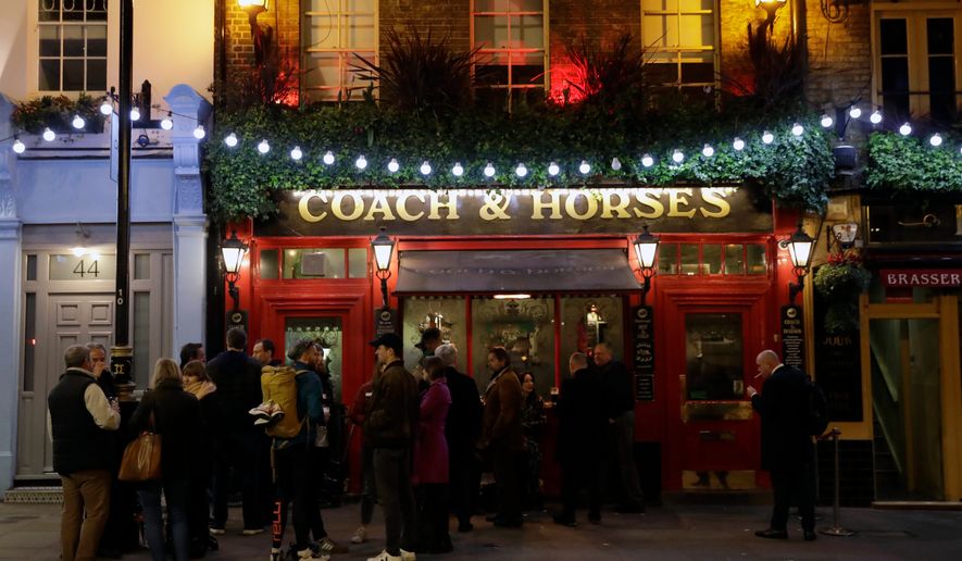 FILE - People stand drinking outside the Coach & Horses pub on Saint Patrick's Day in the Covent Garden district of central London, which is a popular tourist area, Tuesday, March 17, 2020. (AP Photo/Matt Dunham, file)