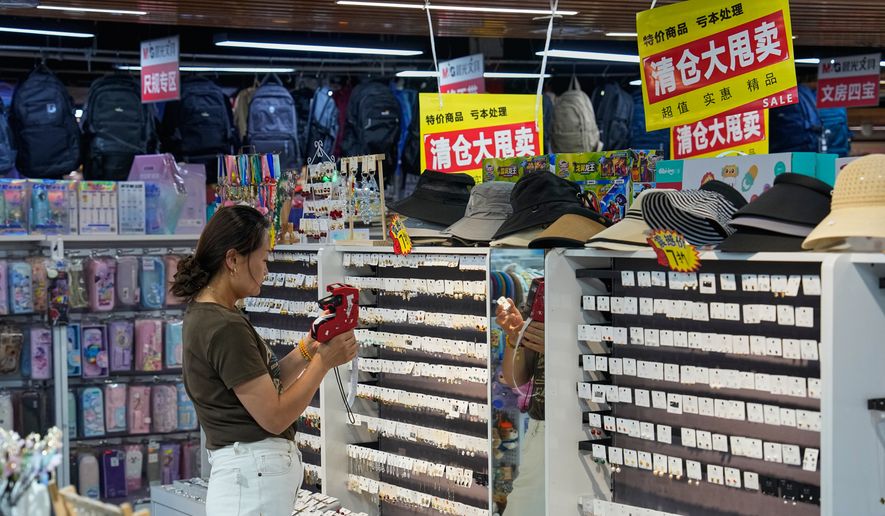 A vendor puts price tag on the ear rings for sale at her store in Beijing, China on Wednesday, July 15, 2026. (AP Photo/Andy Wong)
