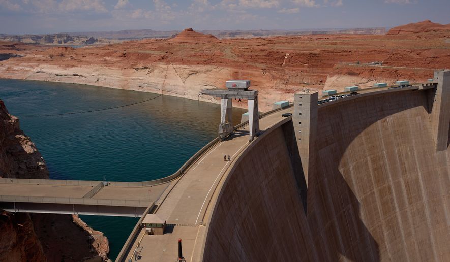 People walk across the Glen Canyon Dam near Lake Powell at the Glen Canyon National Recreation Area, Tuesday, July 14, 2026, near Page, Nev. (AP Photo/John Locher)