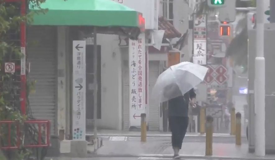 In this image made from video provided by NTV-NNN, a person walks in the rain as typhoon Dolphin approaches the city, in Naha, Japan, Friday, Aug. 7, 2026. (NTV-NNN via AP)