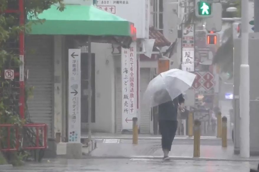 In this image made from video provided by NTV-NNN, a person walks in the rain as typhoon Dolphin approaches the city, in Naha, Japan, Friday, Aug. 7, 2026. (NTV-NNN via AP)