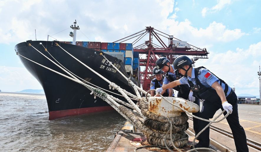 In this photo released by Xinhua News Agency, police officers check the mooring lines of a vessel ahead of Typhoon Dolphin in Beilun District of Ningbo City, east China's Zhejiang Province, on Aug. 7, 2026.(Hu Jiajie/Xinhua via AP)