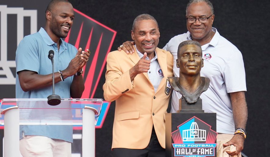 Former NFL player Roger Craig, center, unveils his bust with son, Roderick Craig, left, and Jamie Williams during the Pro Football Hall of Fame induction ceremony at the Pro Football Hall of Fame, in Canton, Ohio, Saturday, Aug. 8, 2026. (AP Photo/Sue Ogrocki)