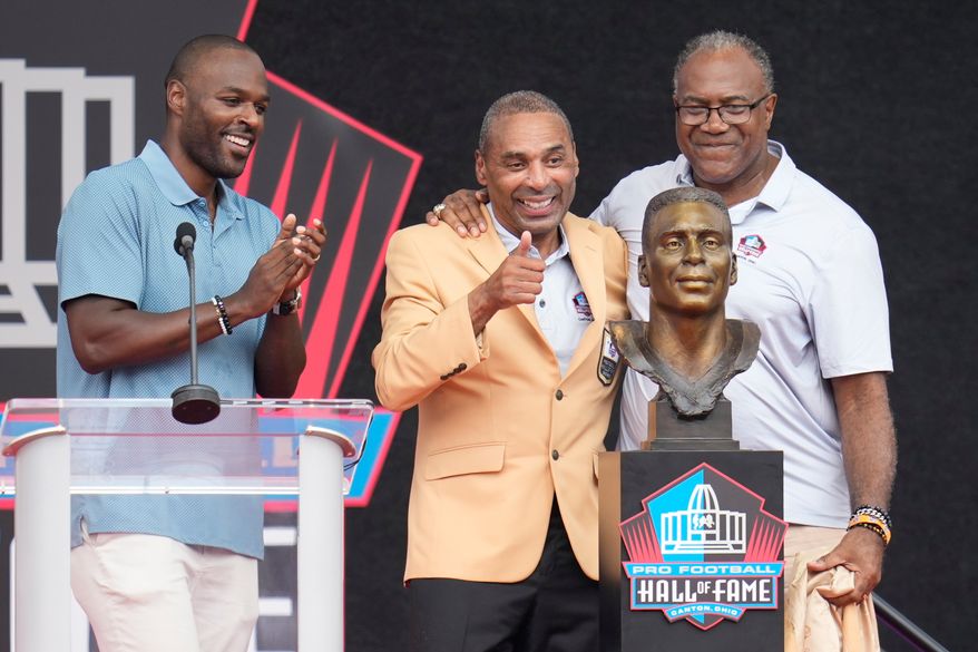 Former NFL player Roger Craig, center, unveils his bust with son, Roderick Craig, left, and Jamie Williams during the Pro Football Hall of Fame induction ceremony at the Pro Football Hall of Fame, in Canton, Ohio, Saturday, Aug. 8, 2026. (AP Photo/Sue Ogrocki)