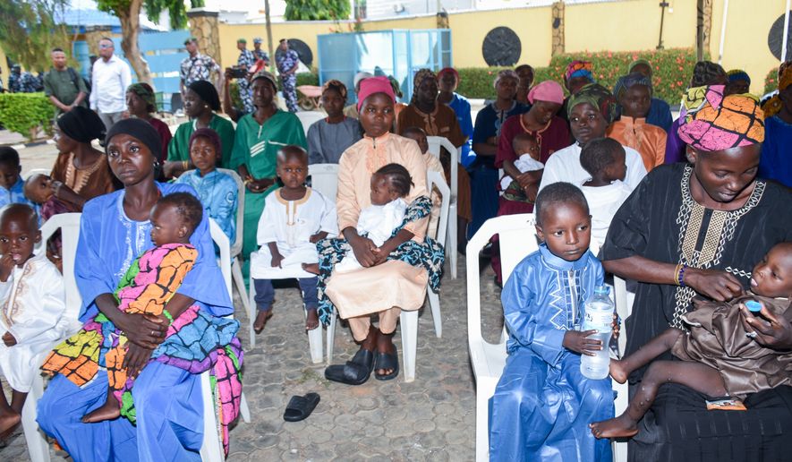 Women and children sit in the courtyard of a hotel where they are staying while waiting for the state governor to address them in Ilorin, Nigeria, Friday, Aug. 7, 2026, after being rescued from a forest where they were held following their abduction from the Woro community by gunmen in February. (AP Photo/Abubakar Khadijat)