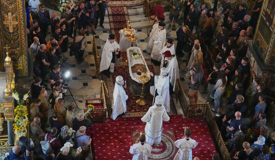 Priests preside over a farewell ceremony for Oleksiy Yukov, who was fatally wounded while exhuming bodies of killed soldiers in the frontline in Donetsk region, in St. Volodymyr Cathedral in Kyiv, Ukraine, Saturday, Aug. 8, 2026. (AP Photo/Efrem Lukatsky)