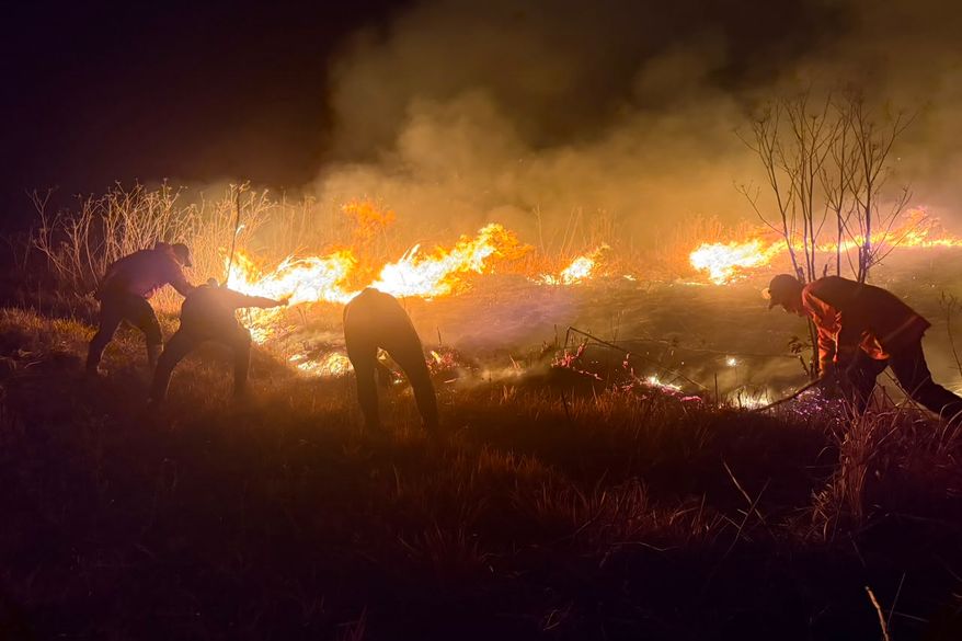 In this photo released by the East Java Regional Disaster Mitigation Agency, firefighters attempt to extinguish a wildfire that razes through Mount Bromo National Park in Probolinggo, Indonesia on Saturday, Aug. 8, 2026. (East Java Regional Disaster Mitigation Agency via AP)