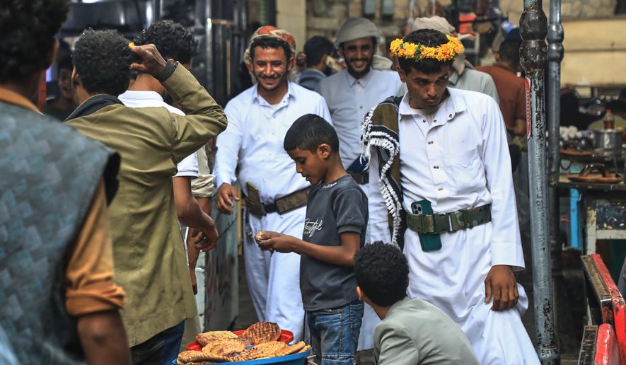 People walk past a boy selling bread at a street market in Sanaa, Yemen, Saturday, Aug. 8, 2026. (AP Photo/Osamah Abdulrahman)