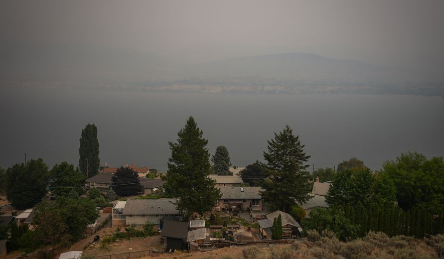 Houses are seen overlooking Okanagan Lake as smoke from the Bald Range wildfire blankets the area, in Penticton, British Columbia, Sunday, Aug. 9, 2026. (Darryl Dyck/The Canadian Press via AP)
