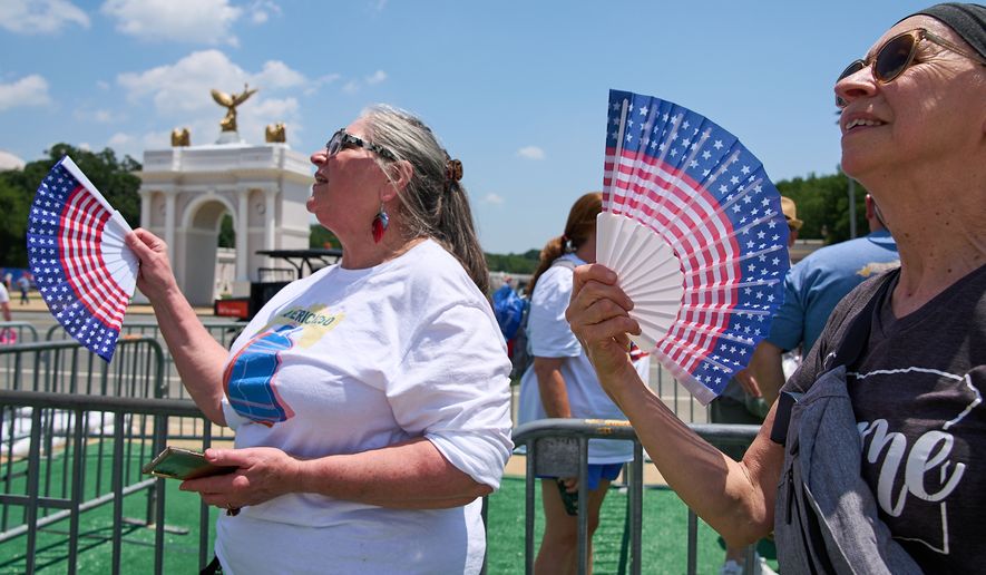 FILE - Mickelina Papotto, of Salem, Ore., left, and Lorie Odegaard, of Gaithersburg, Md., fan themselves while waiting in line for the ferris wheel at the Great American State Fair on the National Mall, July 1, 2026, in Washington. (AP Photo/Jacquelyn Martin, File)