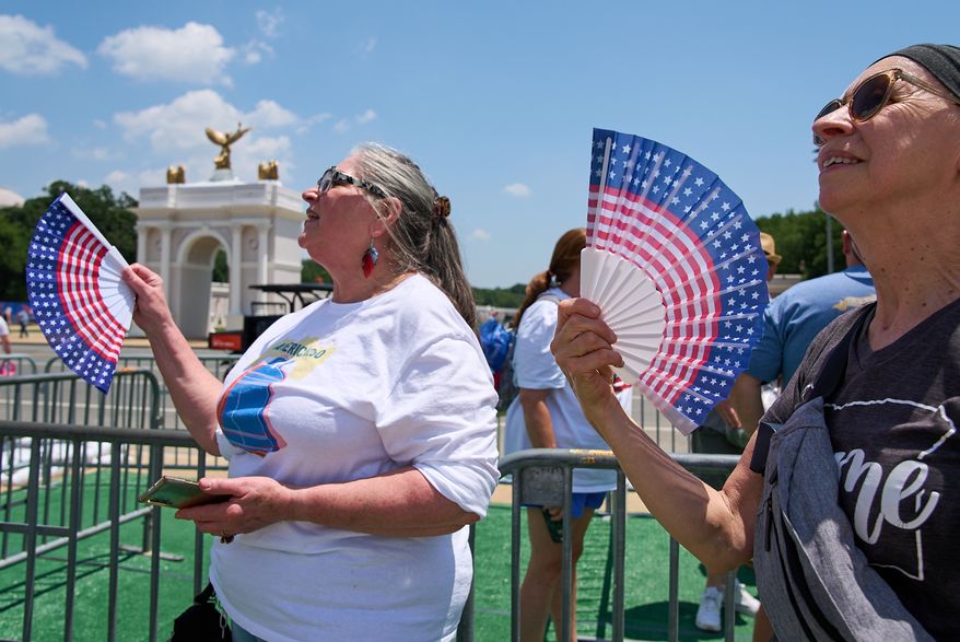 FILE - Mickelina Papotto, of Salem, Ore., left, and Lorie Odegaard, of Gaithersburg, Md., fan themselves while waiting in line for the ferris wheel at the Great American State Fair on the National Mall, July 1, 2026, in Washington. (AP Photo/Jacquelyn Martin, File)