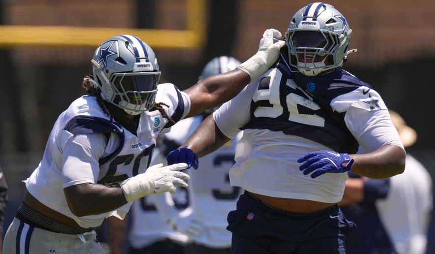 Dallas Cowboys offensive tackle Tyler Guyton, left, holds defensive tackle Quinnen Williams back during the NFL football team's training camp, Saturday, Aug. 1, 2026, in Oxnard, Calif. (AP Photo/Mark J. Terrill)