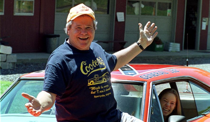 Cooter, actor Ben Jones, sits atop one of the 229 hotrods, named the General Lee, used in the show "Dukes of Hazzard" as ecstatic fan, Aliceson Johnson, of Charlottesville, Va., sits in the driver's seat in front of his store in Sperryville, Va., Tuesday, Aug. 10, 1999. (AP Photo/Steve Helber, File)