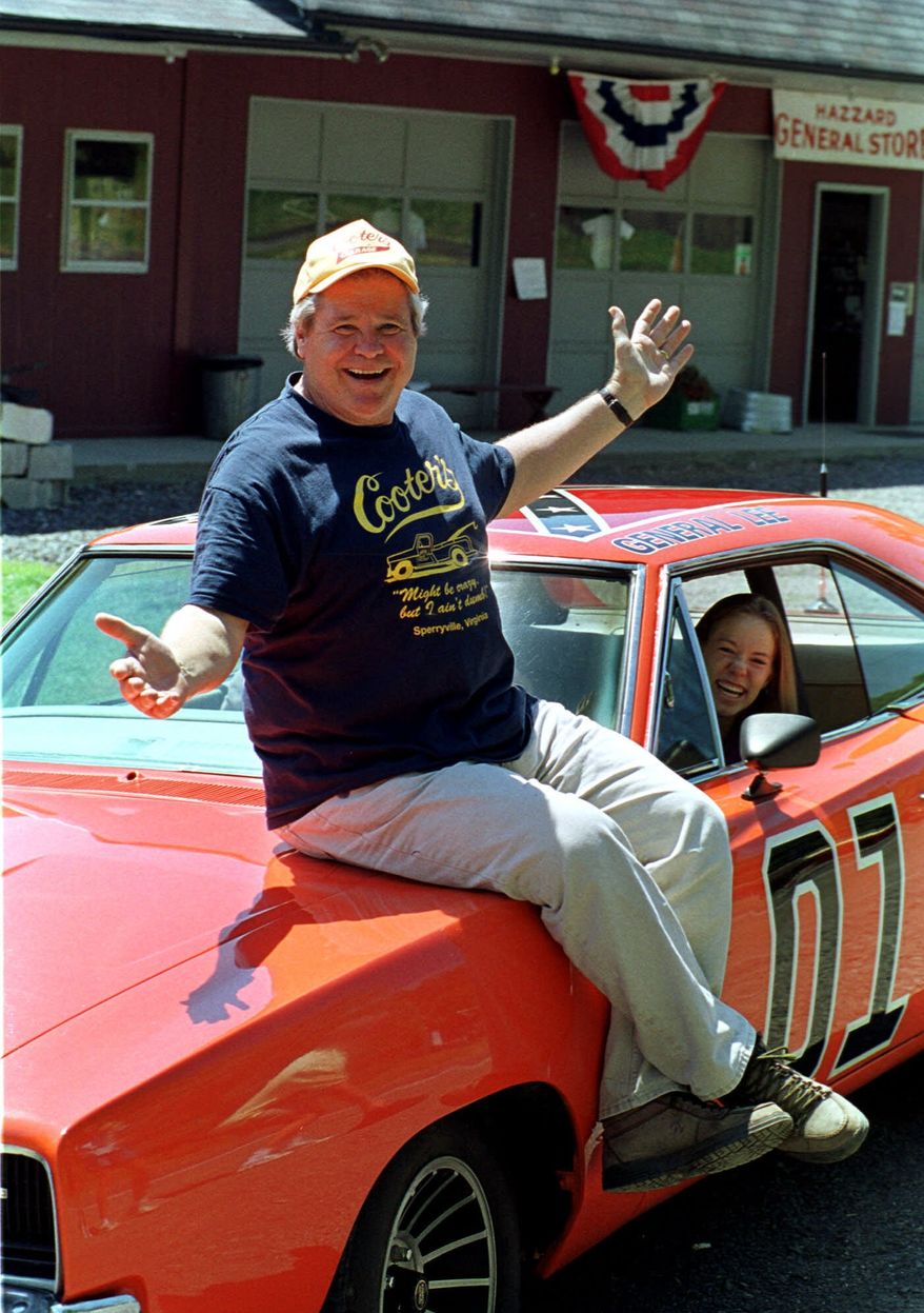 Cooter, actor Ben Jones, sits atop one of the 229 hotrods, named the General Lee, used in the show "Dukes of Hazzard" as ecstatic fan, Aliceson Johnson, of Charlottesville, Va., sits in the driver's seat in front of his store in Sperryville, Va., Tuesday, Aug. 10, 1999. (AP Photo/Steve Helber, File)
