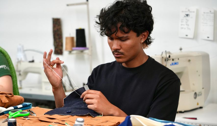 Jesse Sanchez practices sewing during a clothing repair workshop at a Levi's retail store in downtown San Francisco, Wednesday, July 22, 2026. (AP Photo/Terry Chea)
